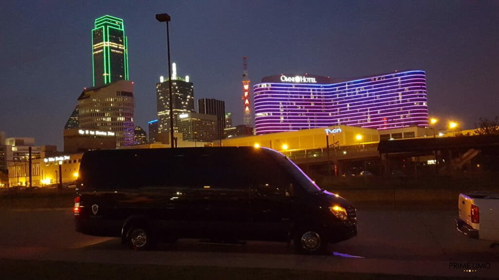 Full side view of black Sprinter with Dallas skyline at night